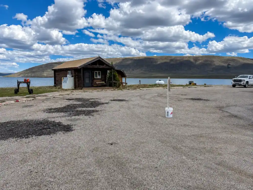 Before photo of deteriorated asphalt parking area and lakeside building at Strawberry Reservoir in Utah before a 14,000-square-foot asphalt paving project by Eckles Paving.