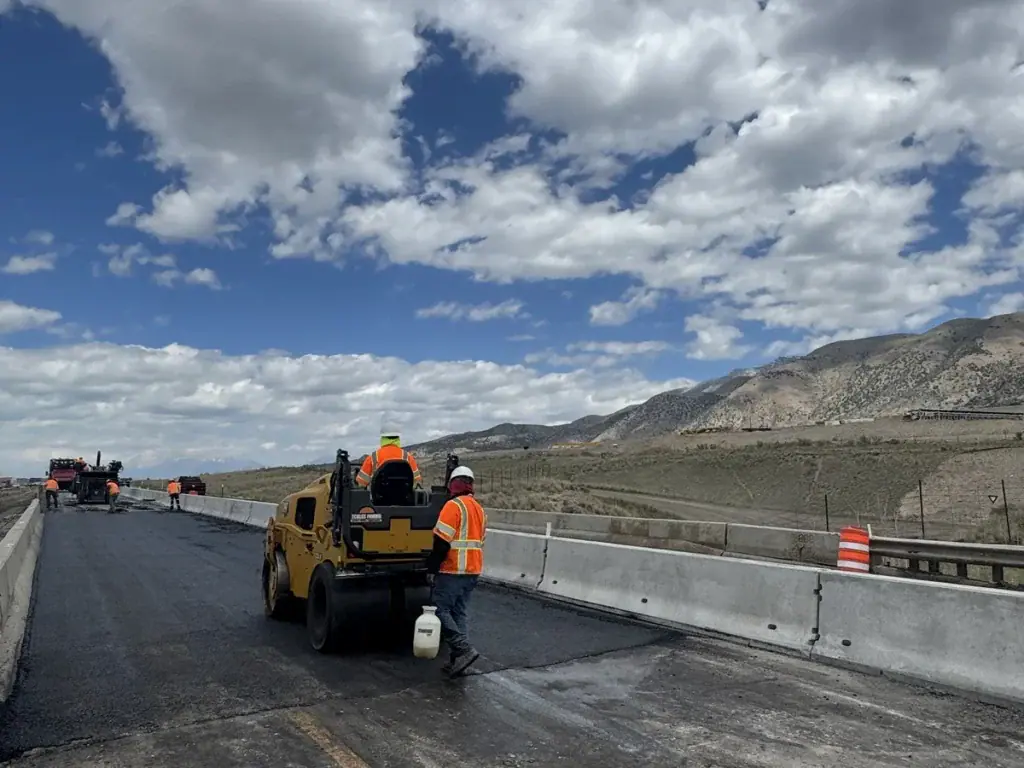 Eckles Paving crew compacting freshly installed asphalt with a roller along I-15 in Mona, Utah.