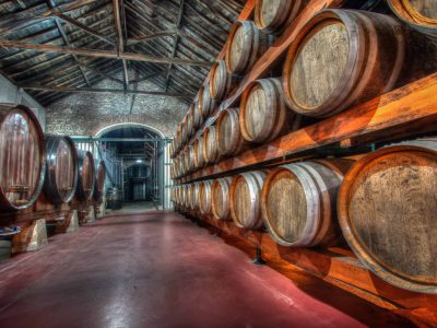 Barricas de vinho tradicionais na histórica "Adega Velha" da vinícola Venâncio da Costa Lima, Portugal, representando a produção de vinhos finos e envelhecimento em madeira.