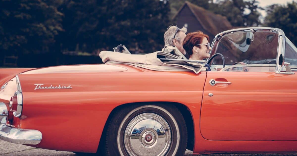 Couple driving a classic car to donate to charity