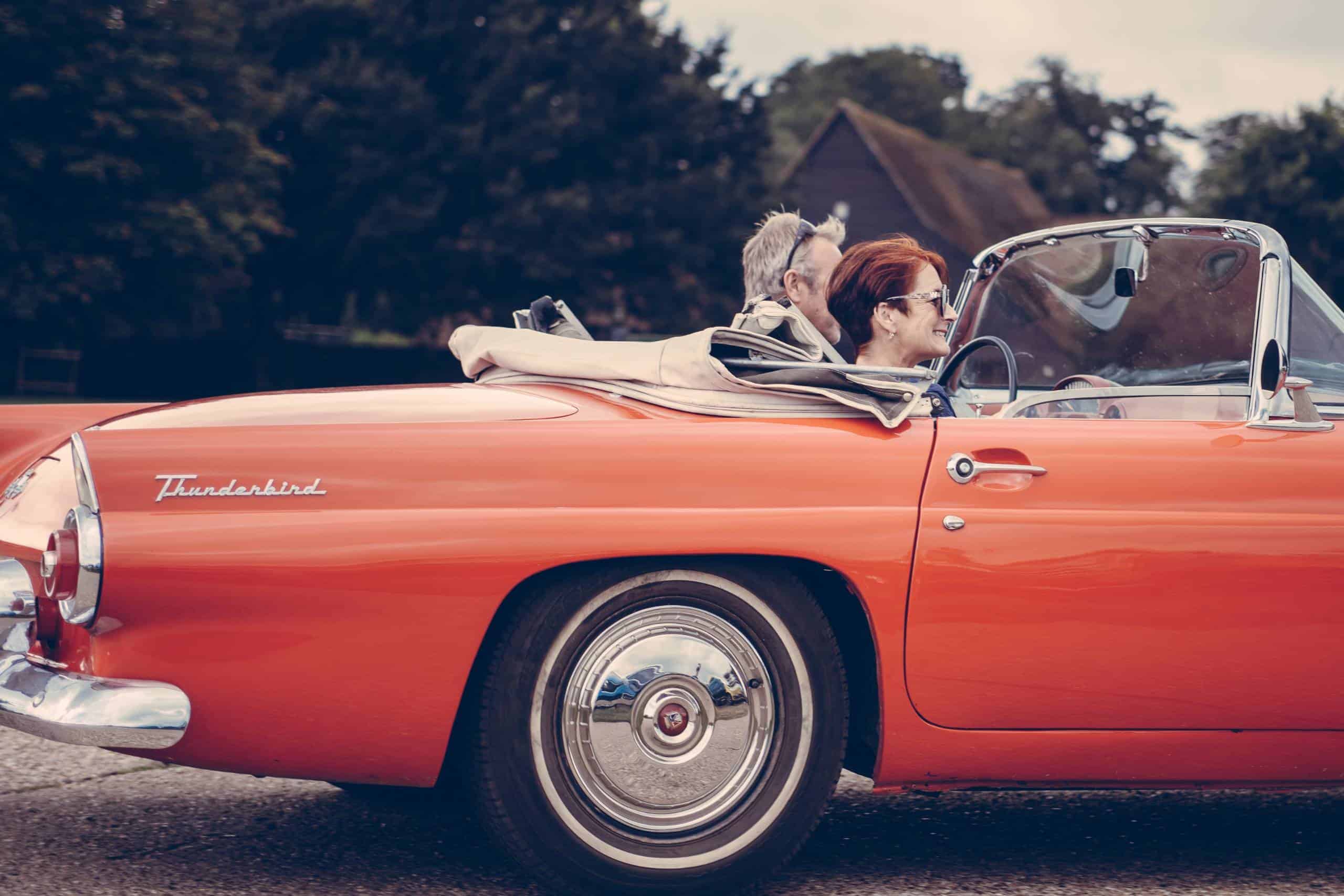 Couple driving a classic car to donate to charity