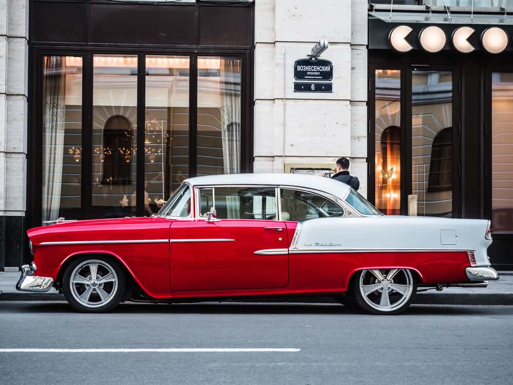 red classic car parked outside of a city building
