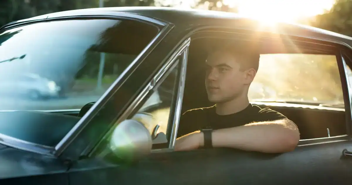 young man driving a collector car