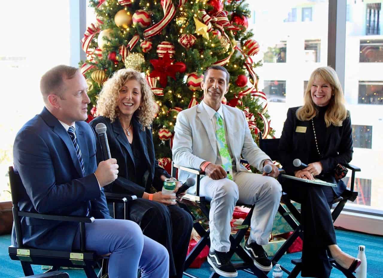 Panel discussion with four people in front of a Christmas tree at WPBgo event.