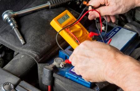 A man testing car battery voltage