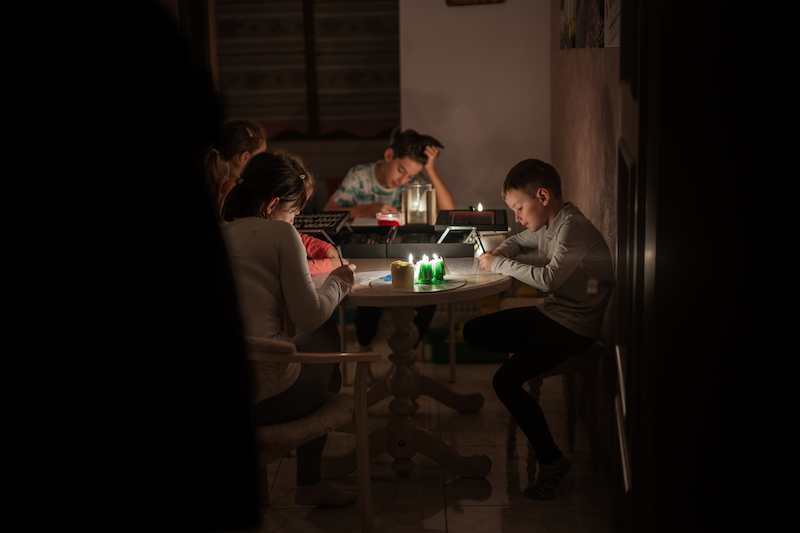 Family Spending Time Together During An Energy Crisis or Power Outage In Minnesota Causing Blackouts. Kids Drawing In Blackout.