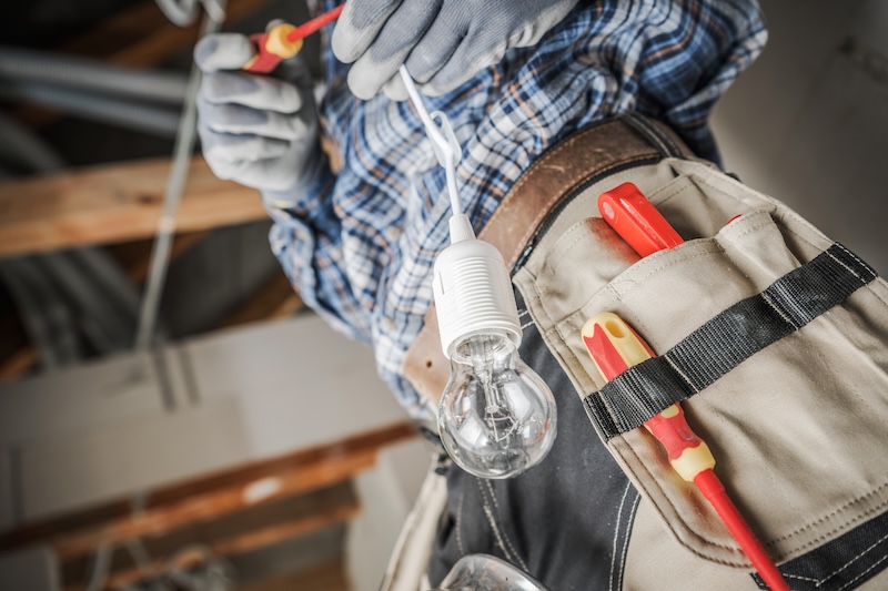 Electrician with lightbulb changing light fixture