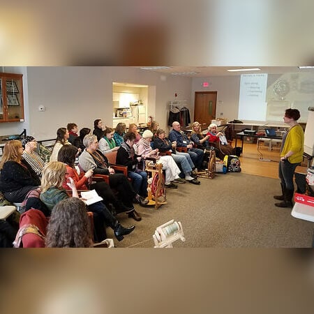 A guild meeting with spinners listening to Alanna Wilcox give a presentation on handspun yarn