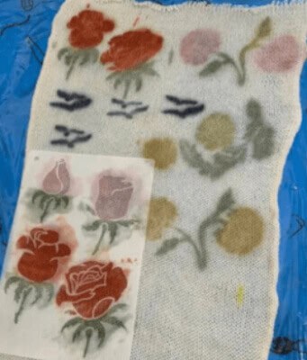 A vibrant floral fabric with red, pink, and green watercolor-style flower designs.