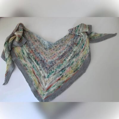Hand-knit multicolored shawl with a tied corner, cozy and stylish accessory.