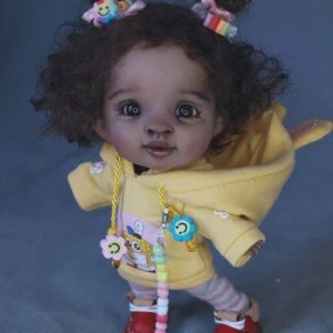 A doll with curly hair wearing a yellow jacket.