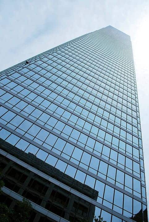 Tall glass skyscraper against cloudy sky.