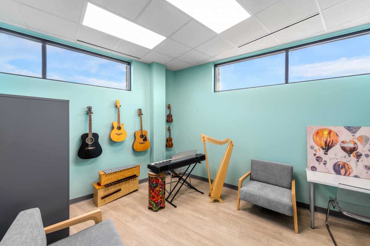 Music room with guitars, keyboard, harp, and artwork.