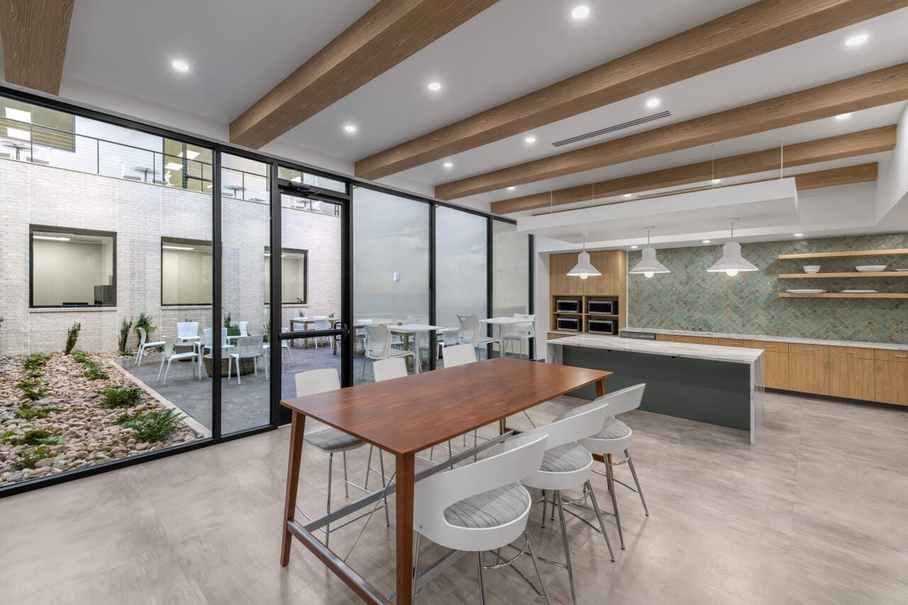 Modern kitchen with large windows and seating area.