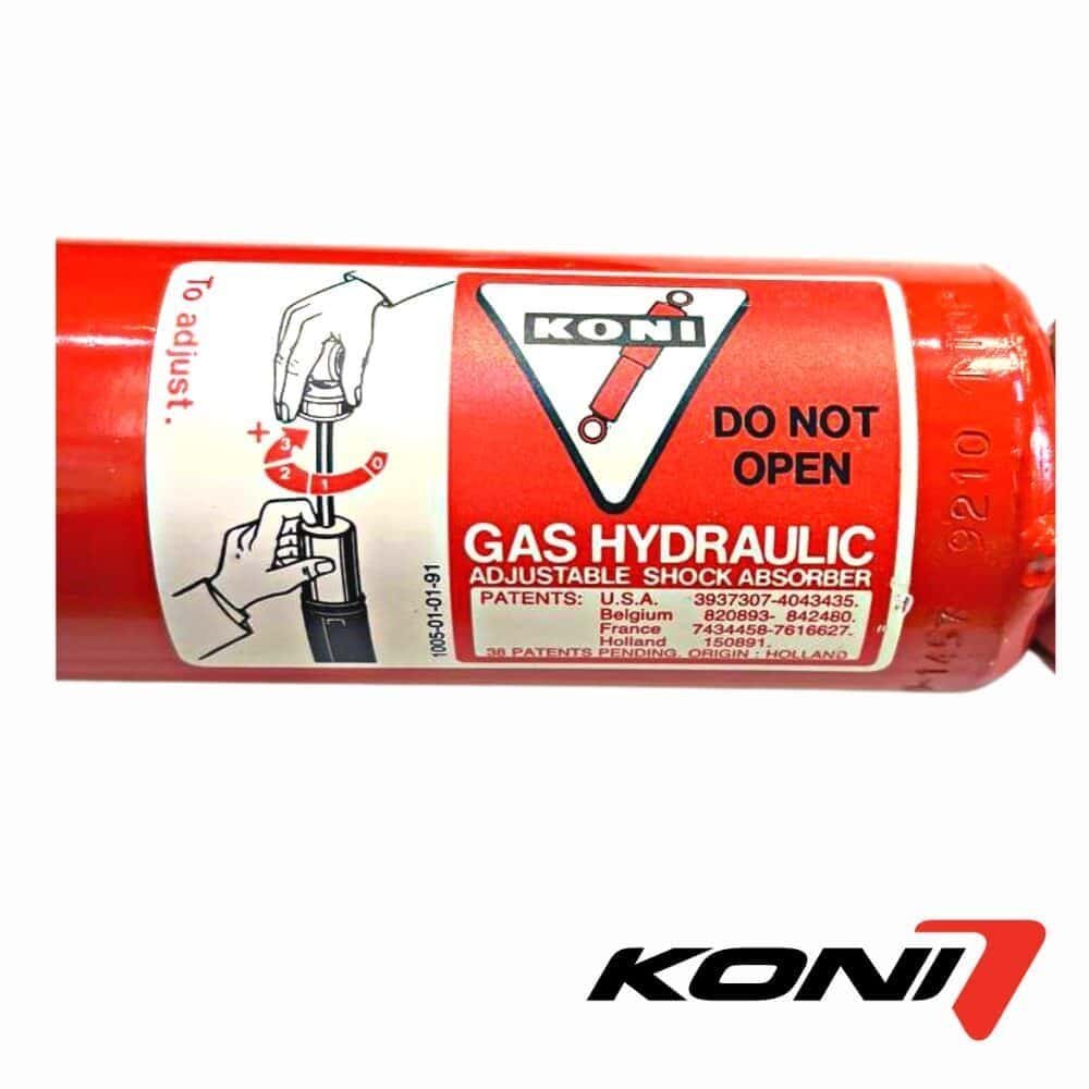 Compressed gas hydraulic shock absorber for industrial use, labeled with safety warnings and brand K.