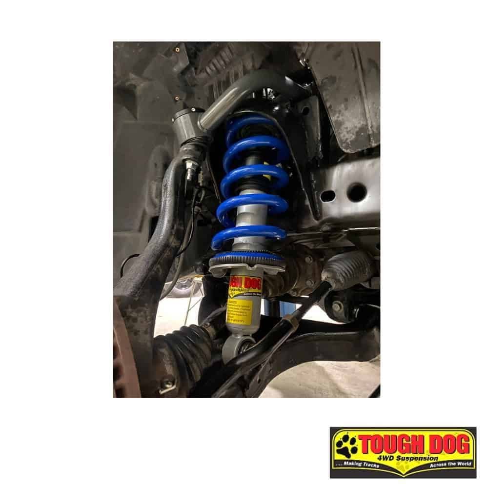 High-performance vehicle suspension with blue coil spring and shock absorber for off-road durability.