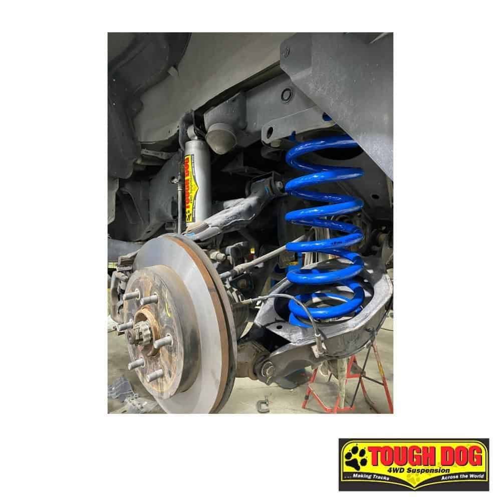 Heavy-duty vehicle suspension system with blue coil spring and shock absorber.