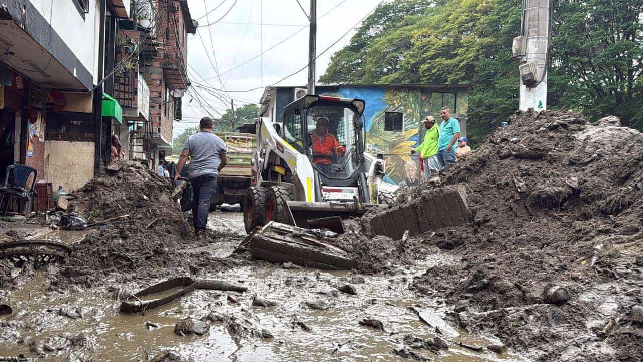 Personal atiende una zona afectada por las lluvias en Medellín con labores de limpieza y remoción de lodo.