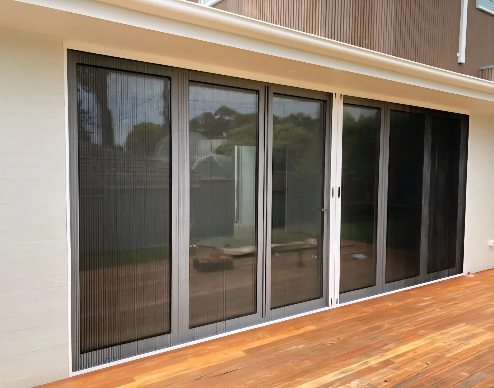 Pleated retractable insect screens across bifold doors onto a timber deck