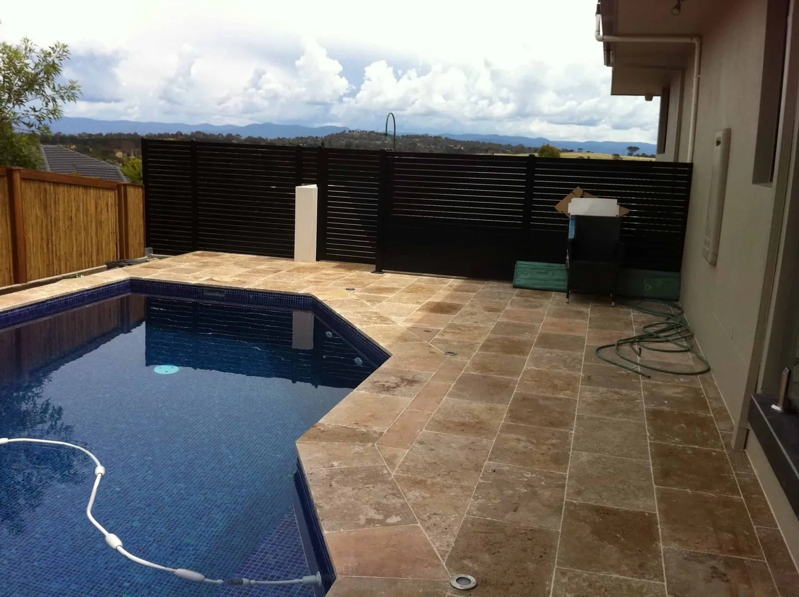 Black slat pool fence and privacy screen beside a backyard pool