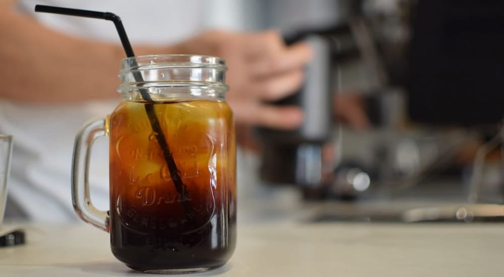 Mason jar with cold brew coffee and a black straw