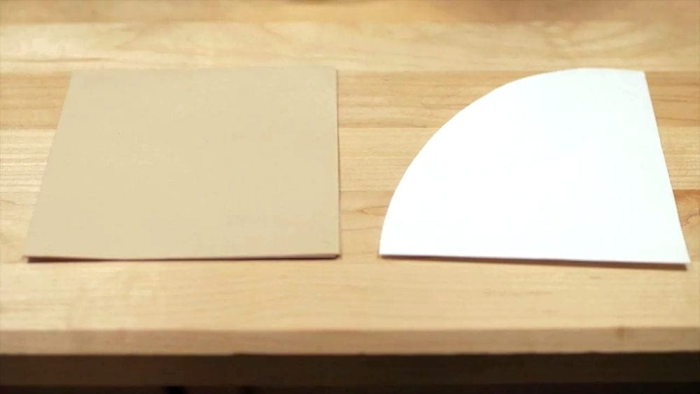 A square brown Chemex filter and a round white filter on a wooden table 
