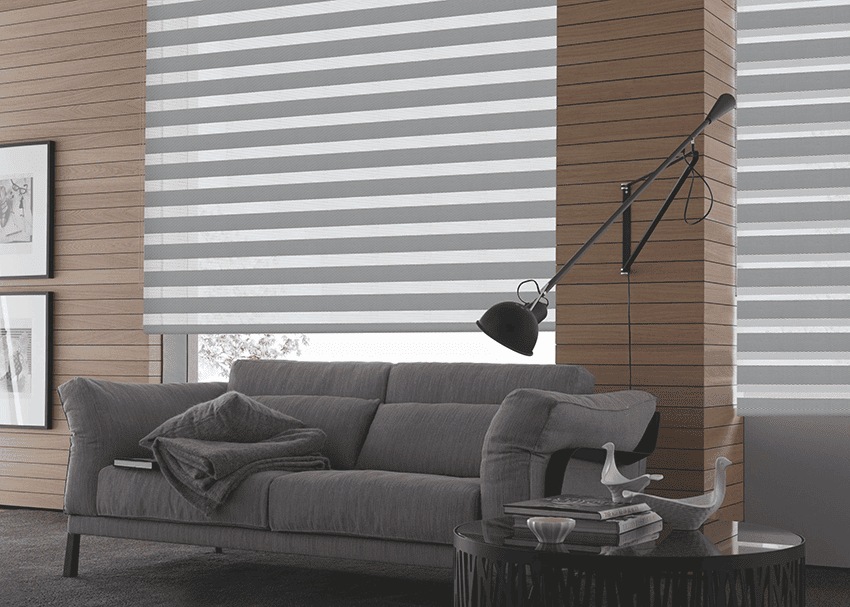 Stylish living room featuring a gray sofa, striped blinds, modern decor, and cozy atmosphere.
