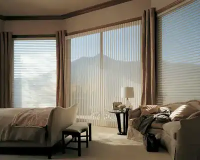 Spacious living room featuring large windows with blinds, overlooking mountain views, cozy furniture, and natural lighting.
