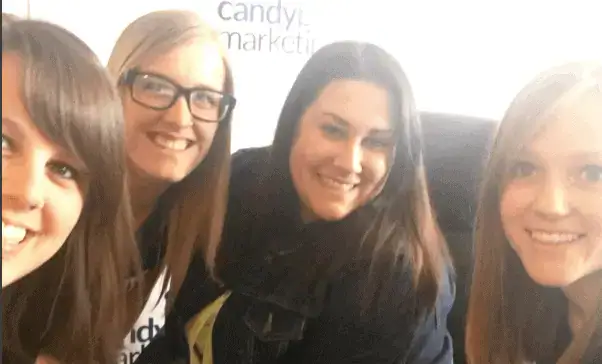 Young women smiling at an event, enjoying a group photo with bright expressions.