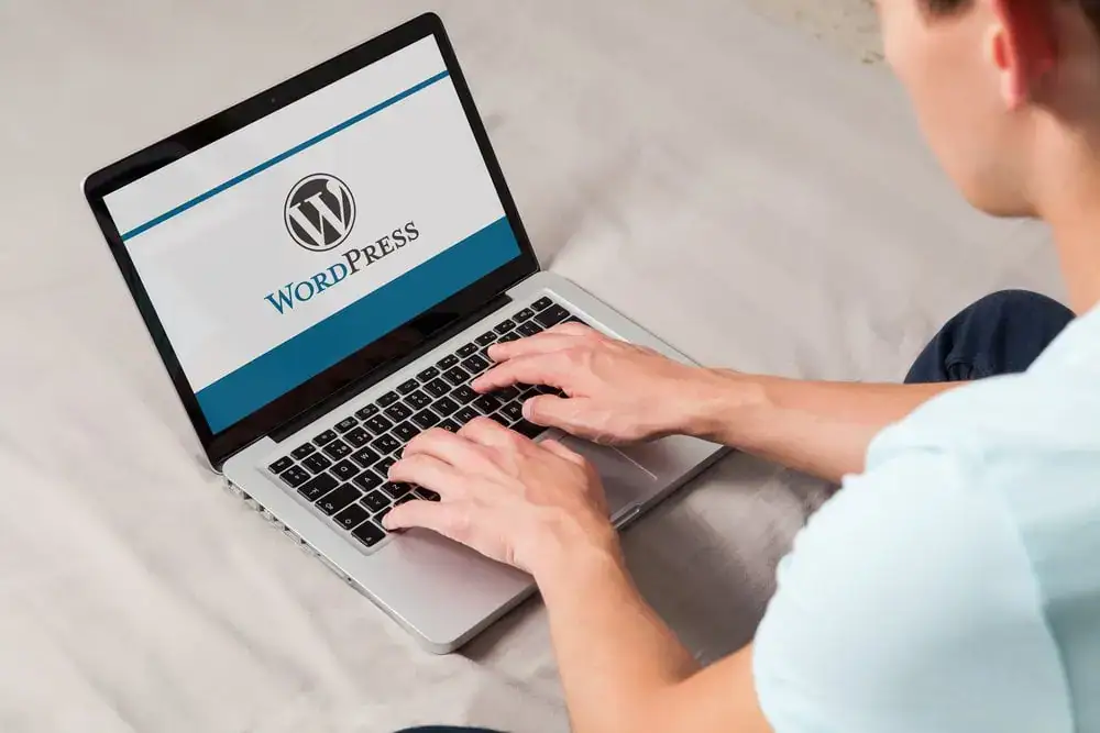 Person working on a laptop with WordPress logo on screen.