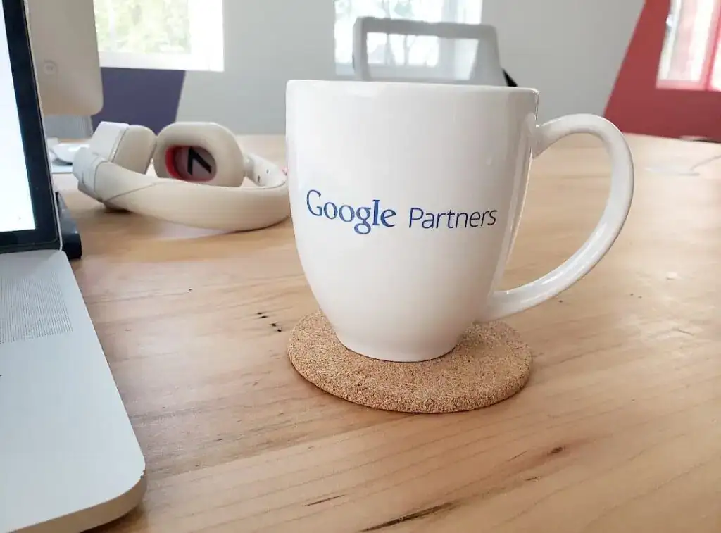 Google Partners mug on a wooden desk with a cork coaster.