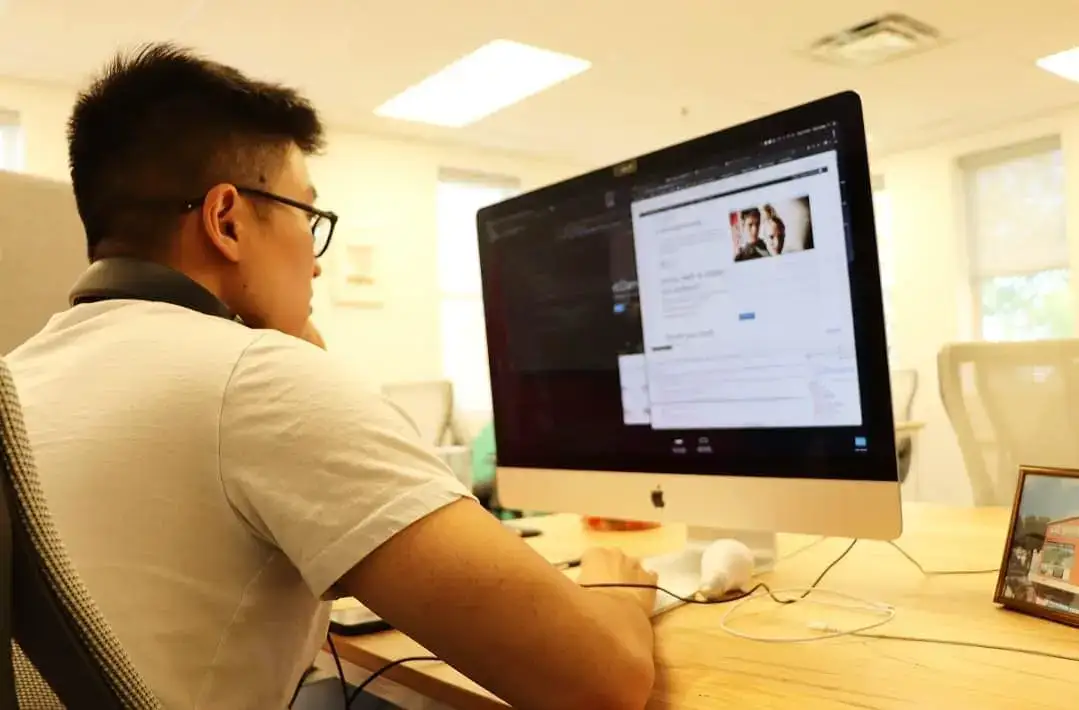 Person working on a desktop computer in a bright, modern office environment.