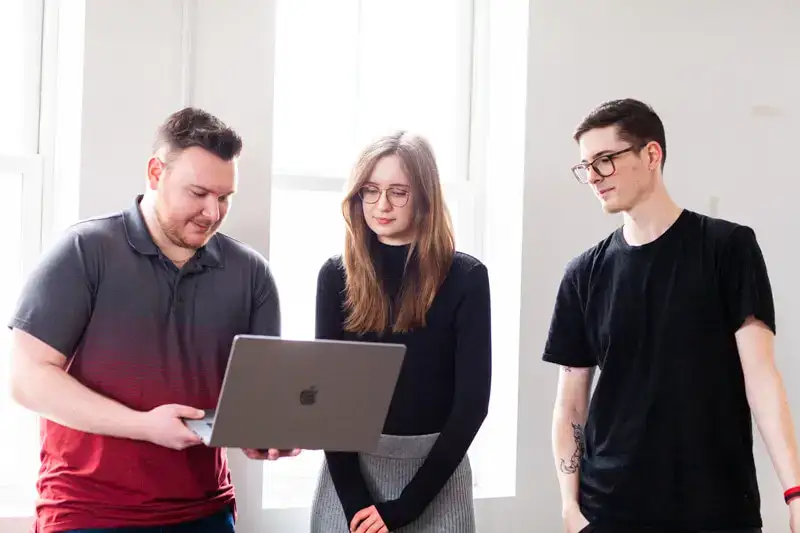 Team collaborating on a project using a laptop in a modern office environment.