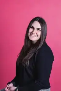 Young woman smiling with long dark hair and black sweater.
