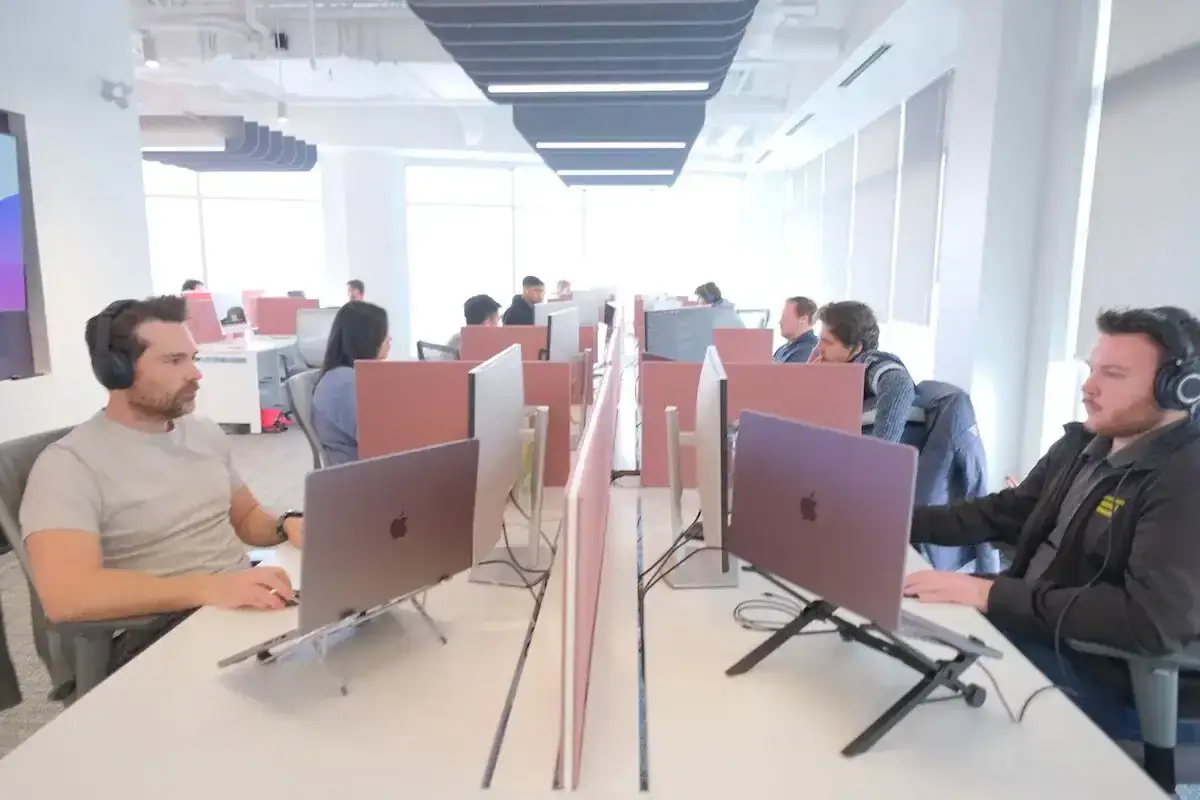 Call center agents working at computers in a bright, open office environment.