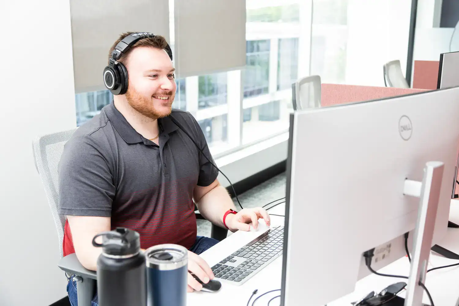 Customer support representative wearing headphones at a desk with a computer.