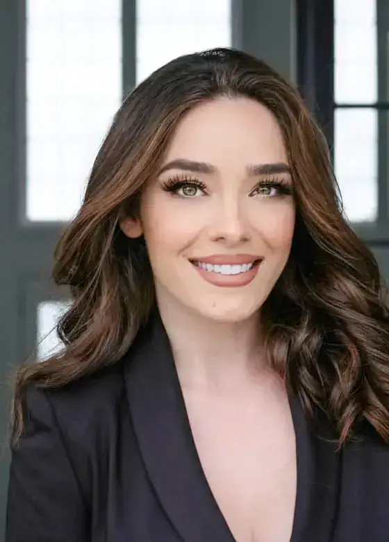 Portrait of a smiling woman with long brown hair in a professional setting.