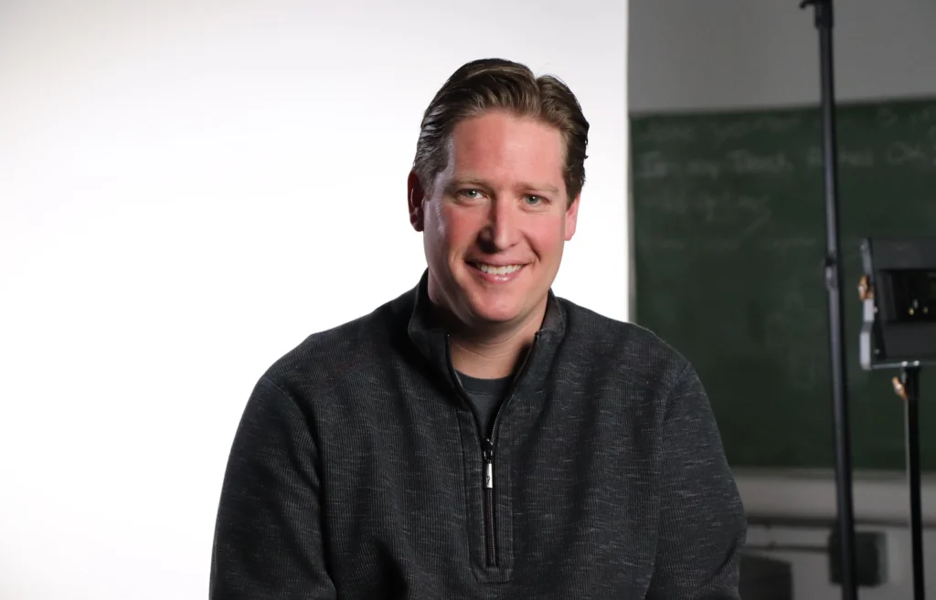 Creative professional smiling in a studio setting with lighting equipment.