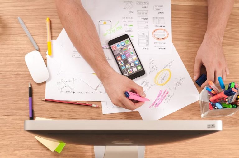 Smartphone on desk with marketing notes and colorful pens, showcasing authority and marketing technology.