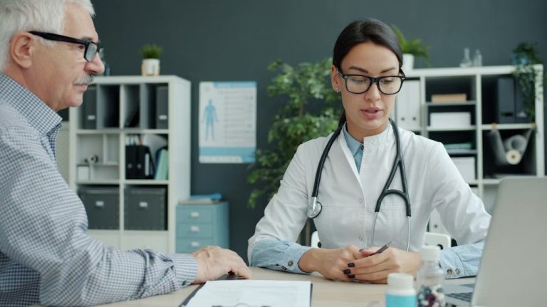 Compassionate female doctor consulting with an elderly patient in a modern medical office.