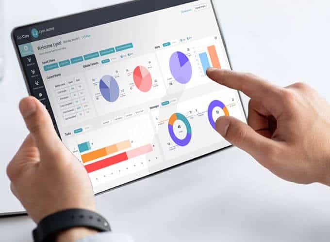 Closeup of a tablet in a Doctors hands with the coachcare dashboard visible on screen