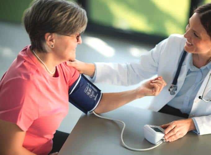Senior woman receives a blood pressure check from a friendly doctor in a bright doctor office