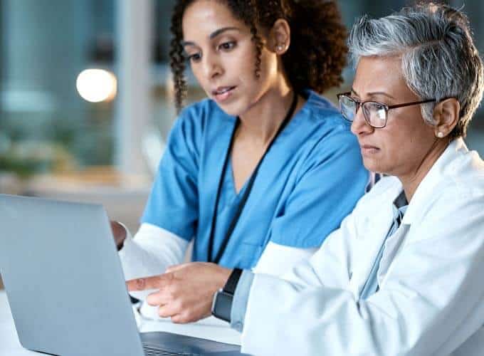 Doctor, team with healthcare and women with laptop, working together and digital hospital schedule or agenda. Technology, medical innovation and collaboration, partnership and cardiovascular surgeon