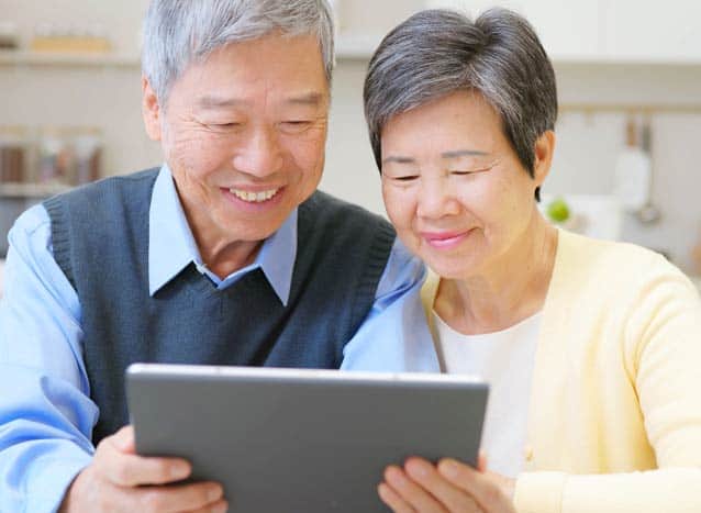 Asian elderly couple use tablet at home at the kitchen table