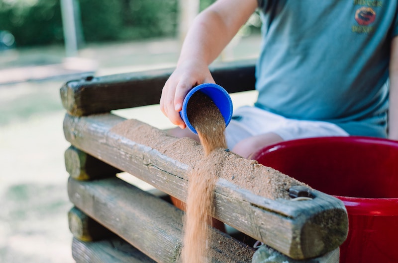 Kind spielt mit Sand auf Spielplatz