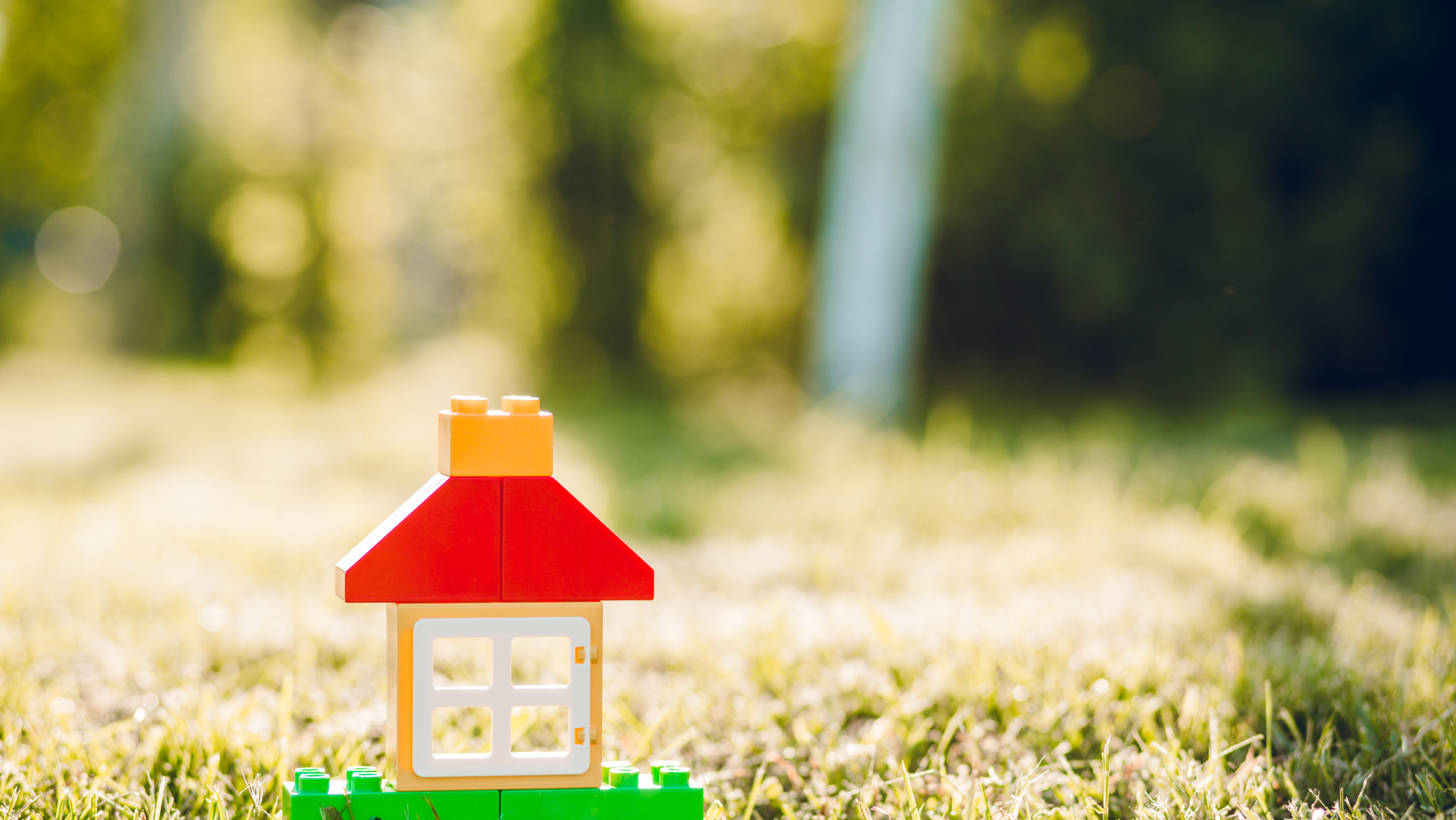 LEGO-Spielzeughaus auf Wiese im Sonnenschein, kindgerecht gestaltet.