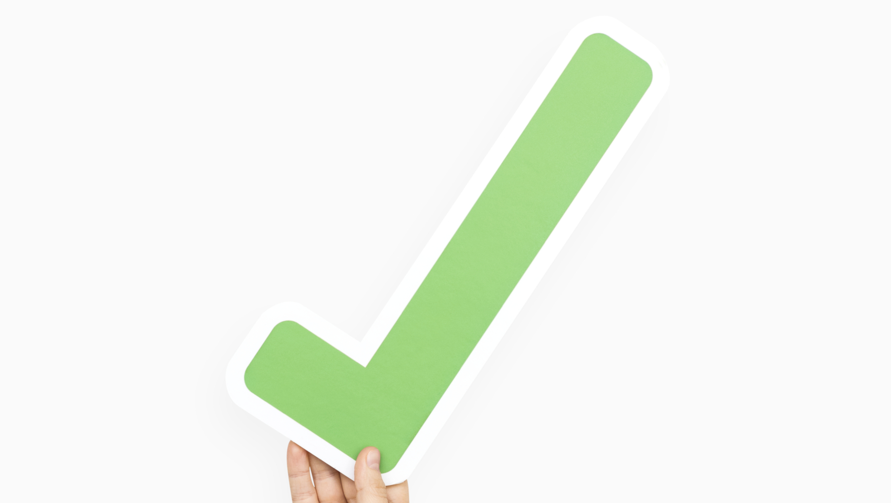 Hand hält grünen Haken, symbolisiert Unterstützung für verpflichtendes Kita-Jahr.