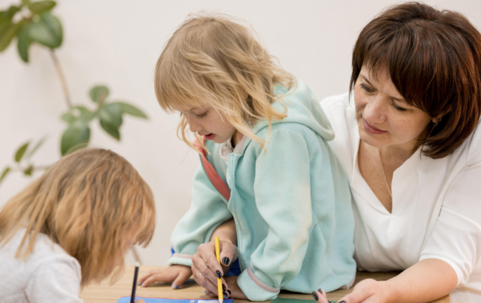 Kinder und Betreuerin beim kreativen Malen im Kindergarten.