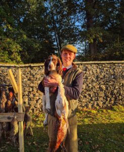 1. Man holding a dog with hunting scene at Erchless Castle Estate, Scotland.