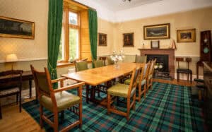 Elegant dining room at Erchless Castle Estate with classic furnishings and tartan carpet, perfect for events.